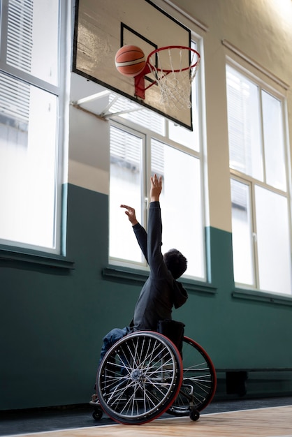 Full shot man in wheelchair playing basketball