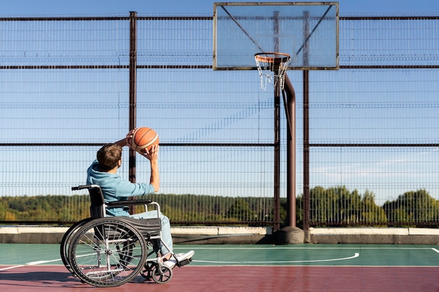 Full shot man in wheelchair playing basketball