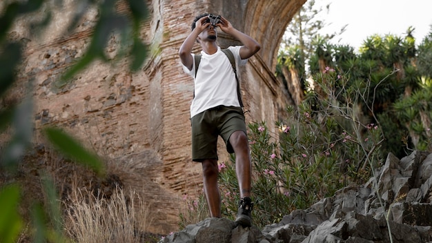 Full shot man with binocular in nature