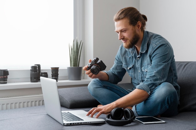 Foto gratuita uomo pieno del colpo con la macchina fotografica e il computer portatile