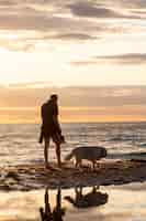 Foto gratuita uomo a tutto campo con cane carino sulla spiaggia