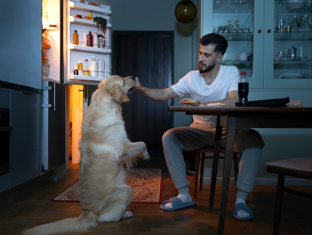 無料写真 キッチンで犬と一緒にフルショットの男
