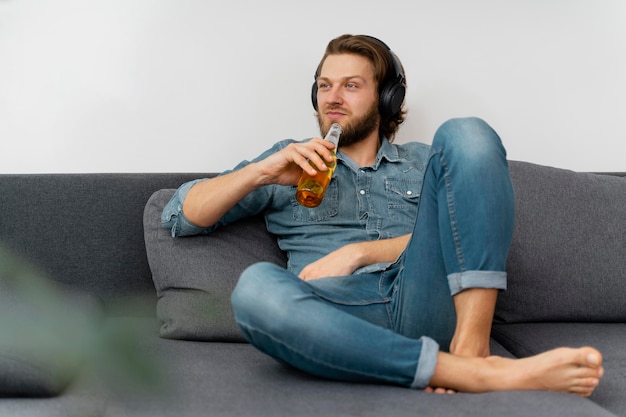Full shot man with drink and headphones