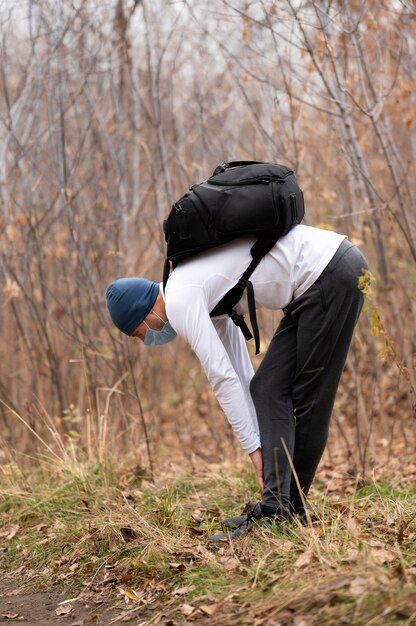 Full shot man with face mask and backpack in the woods