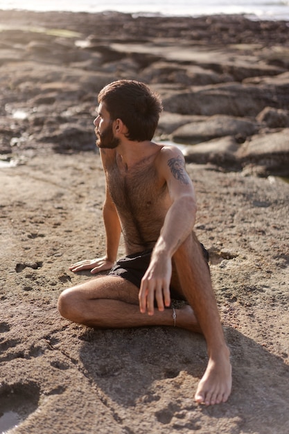 Бесплатное фото Полный выстрел мужчина с волосатой грудью на берегу моря