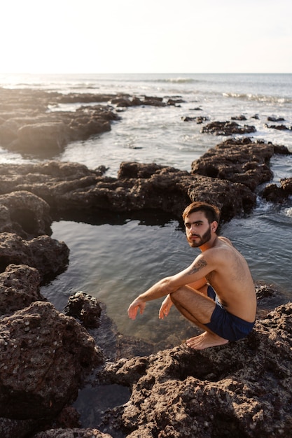 海辺で毛むくじゃらの胸を持つフルショットの男