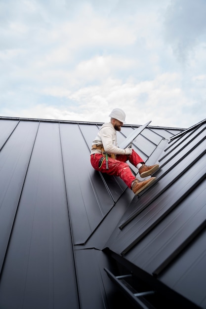 Free photo full shot man with helmet sitting on roof