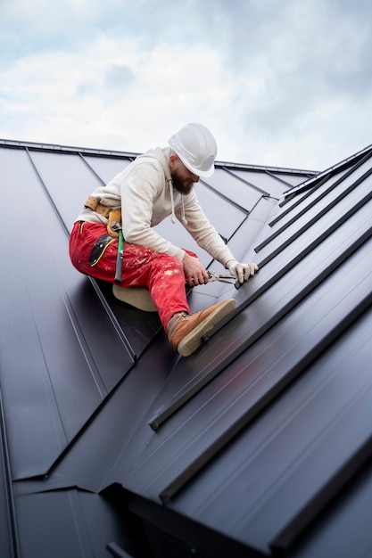 Free photo full shot man with helmet working on roof