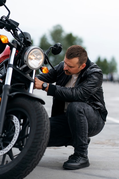 Full shot man with motorbike outdoors