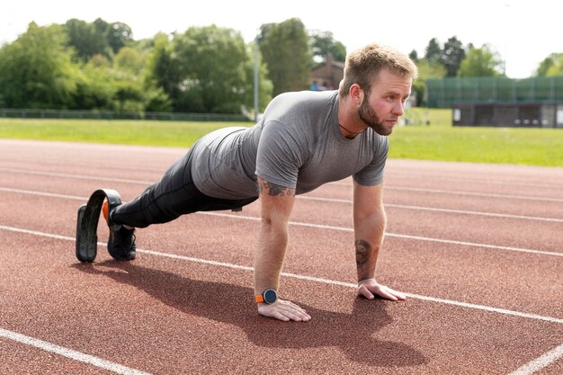 Full shot man with prosthetic leg doing plank