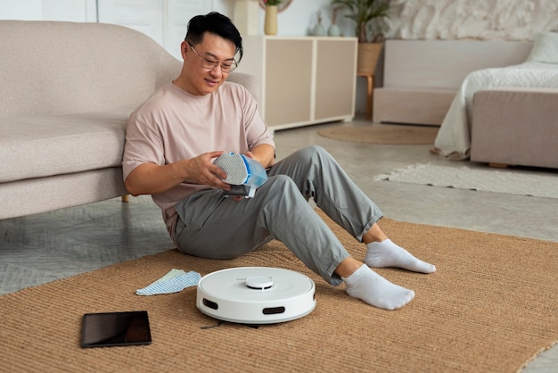 Full shot man with robotic vacuum cleaner at home