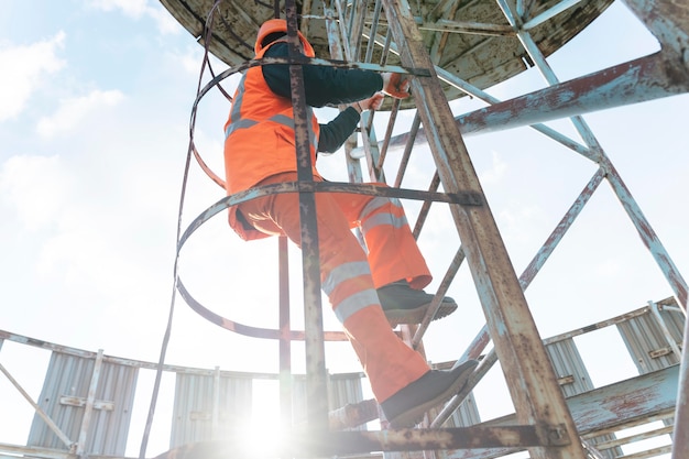 Uomo pieno del colpo con attrezzatura di sicurezza sulla scala