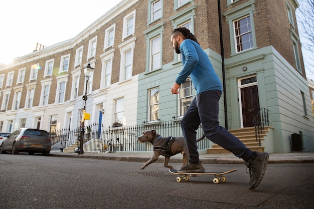 Free photo full shot man with skateboard and dog