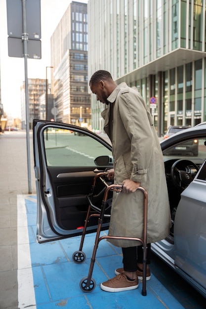 Free photo full shot man with walking frame and car