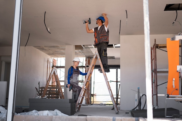 Free photo full shot man and woman standing on ladder