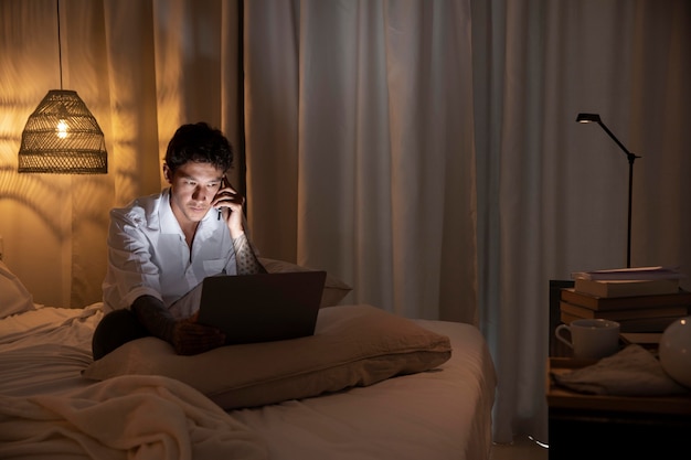 屋内でラップトップに取り組んでいるフルショットの男