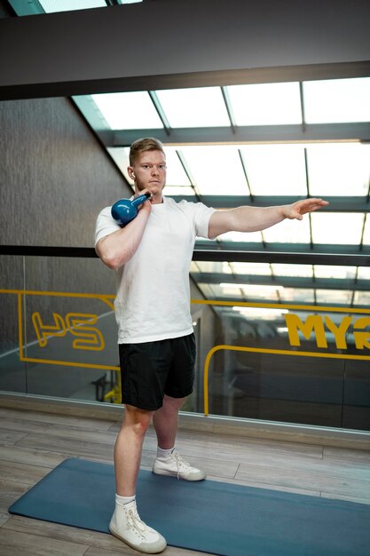 Full shot man working out with kettlebell