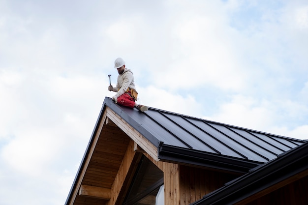 Foto gratuita uomo a tutto campo che lavora sul tetto