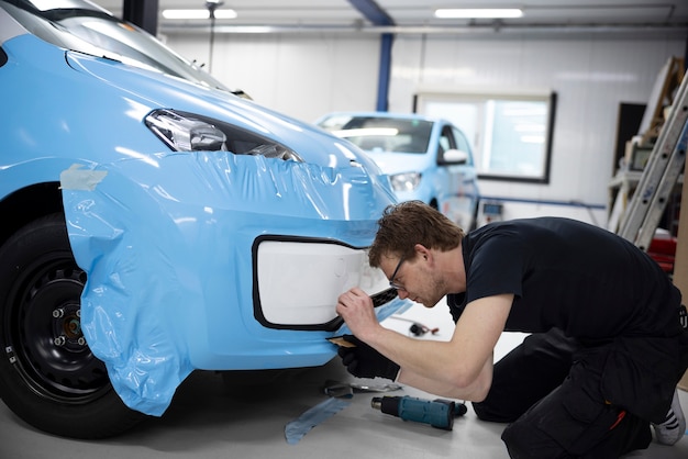 屋内で車を包むフルショットの男