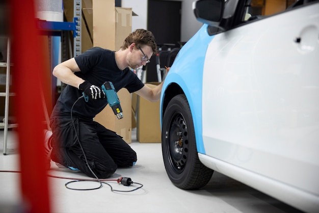 Uomo a tutto campo che avvolge l'auto con la copertura blu