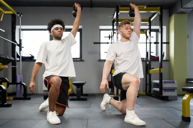 Full shot men exercising with kettlebells