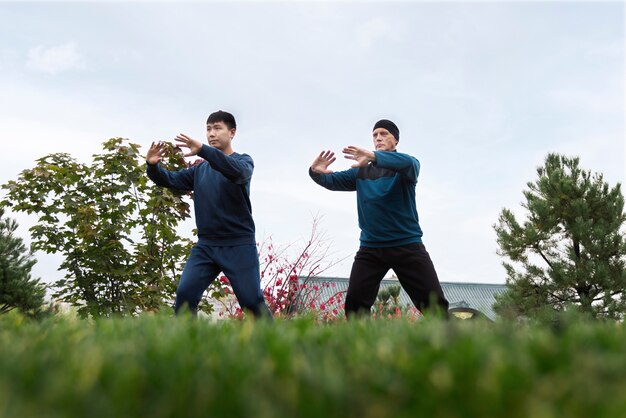 Full shot men practicing tai chi outdoors