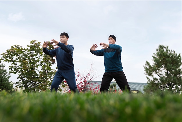 Full shot men practicing tai chi outdoors