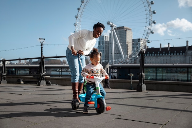 Foto gratuita madre a tutto campo e bambino carino sul triciclo