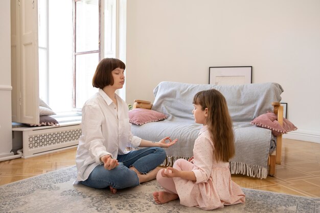 Полный снимок мать и дочь медитируют