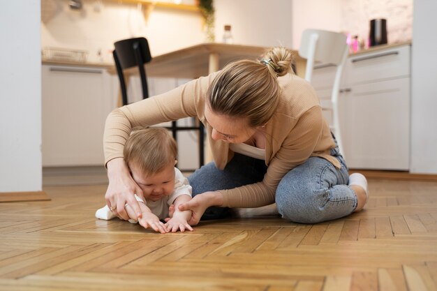 Full shot mother helping baby crawl