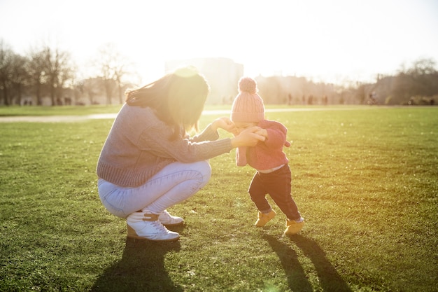 子供が歩くのを助けるフルショットの母親