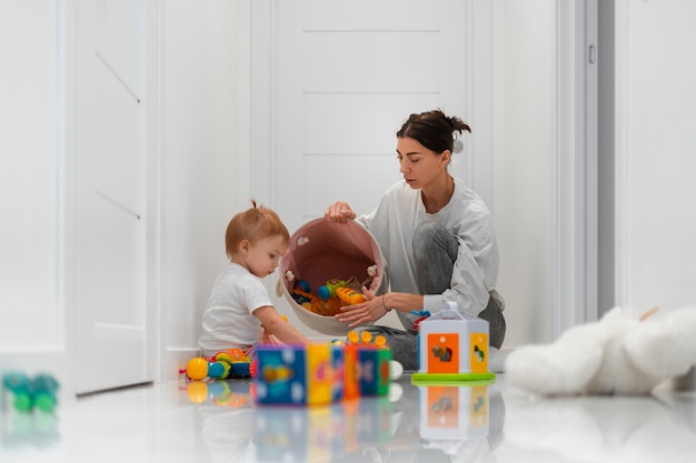 Foto gratuita madre della foto a figura intera che si siede sul pavimento