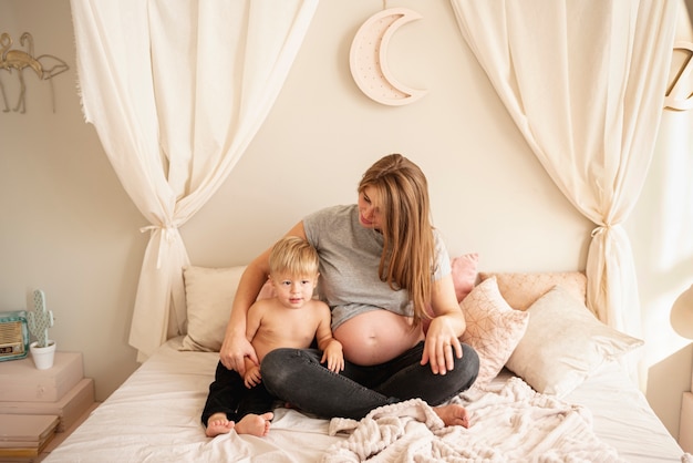 Full shot mother and son sitting in bed