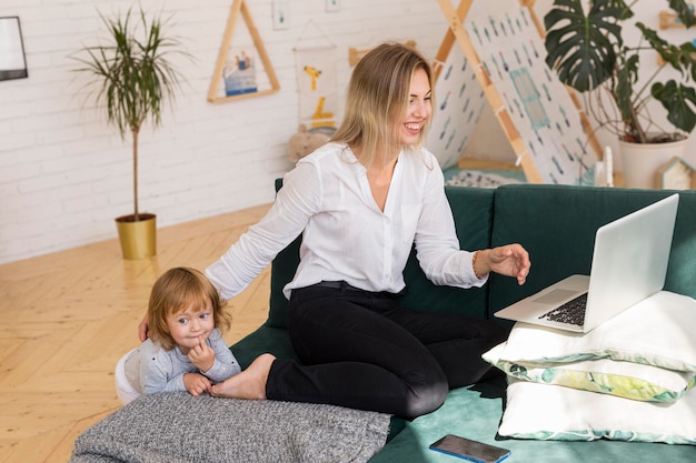 Full shot mother with kid working at home