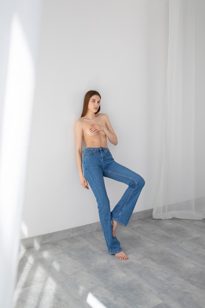 Foto gratuita donna nuda del colpo pieno che posa in jeans