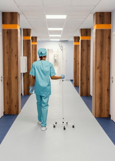 Foto gratuita infermiera del colpo pieno che cammina sul corridoio
