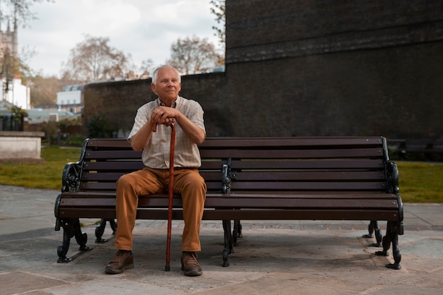 Полный выстрел старик сидит на скамейке
