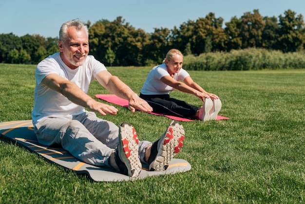 Full shot old people stretching together