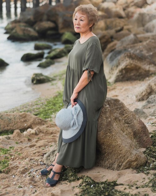 Full shot old woman standing near rock