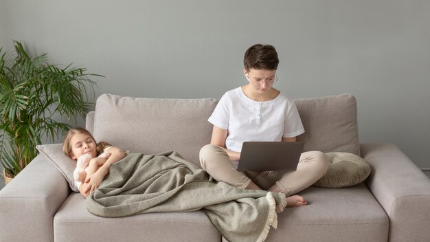 Full shot parent and kid on sofa