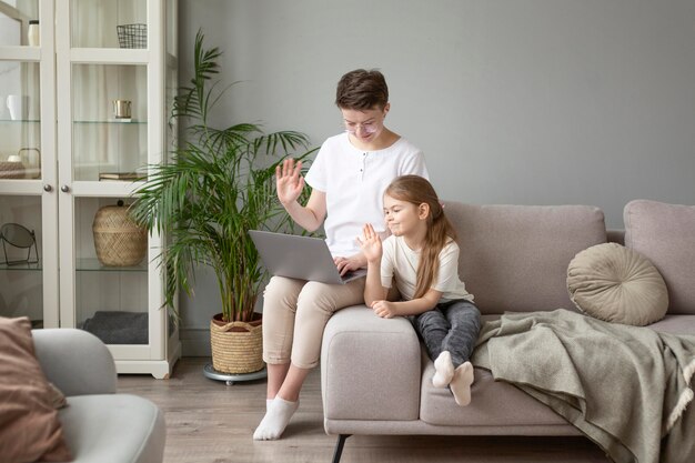 Full shot parent and kid waving at laptop