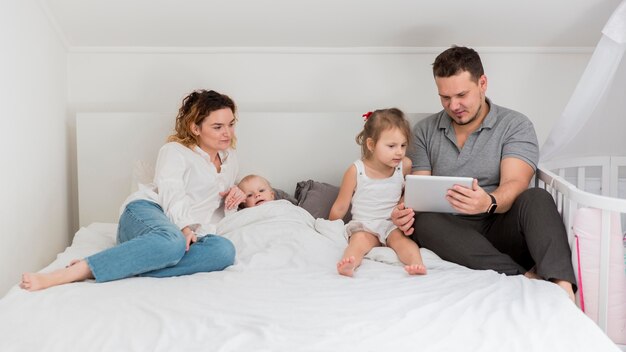 Full shot parents in bed with kids