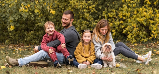 Full shot parents, kids and dog outdoors