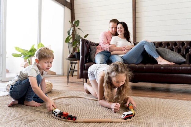 Full shot parents watching children play