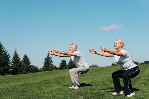 Full shot people doing squats outdoors