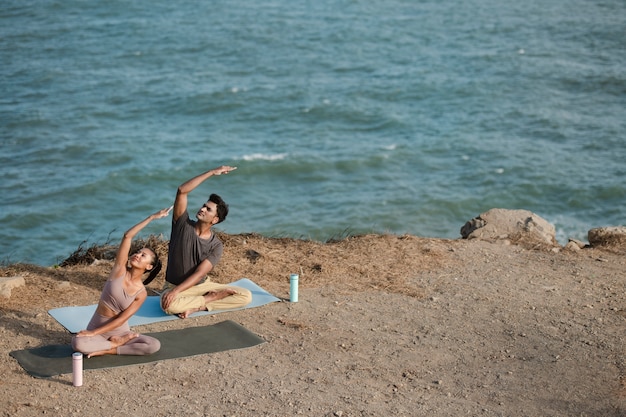 Full shot people doing yoga together in nature