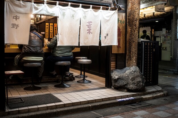 Full shot people eating at japanese street food restaurant