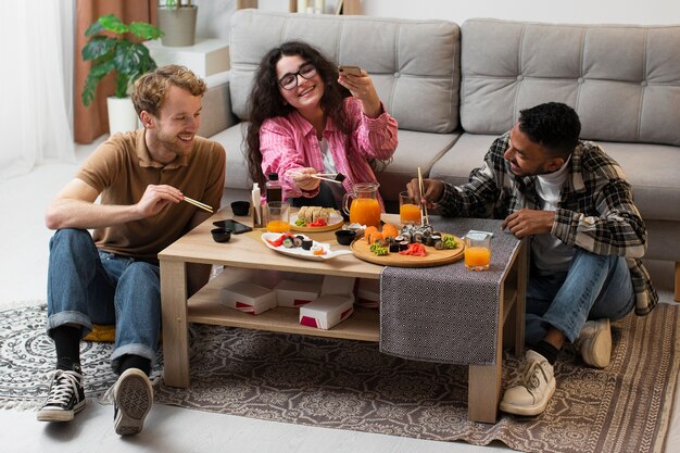 Full shot people eating sushi at home