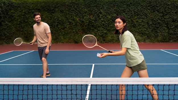 Free photo full shot people playing badminton