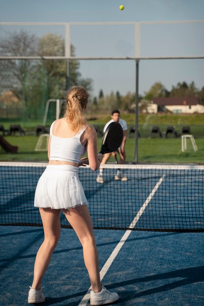 Full shot people playing paddle tennis outdoors